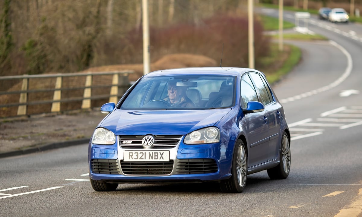 Volkswagen Golf azul circulando por una avenida urbana moderna